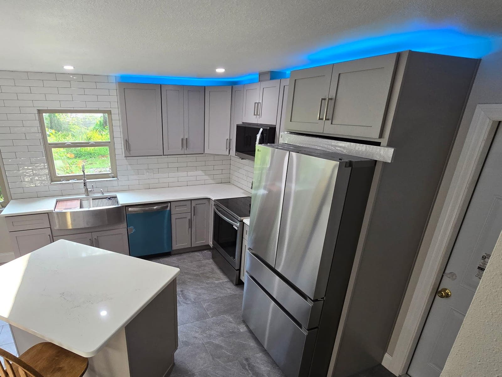 Gray shaker kitchen with a stainless farmhouse sink, quartz counters, and subway tile backsplash