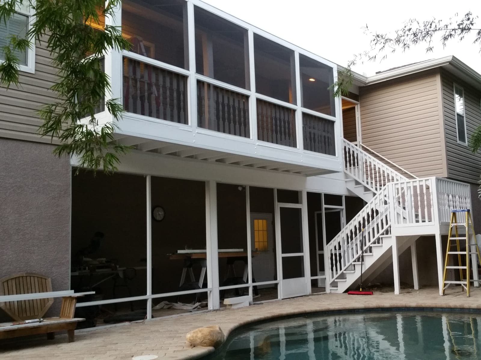 Finished two story screened porch addition with painted railings overlooking a pool