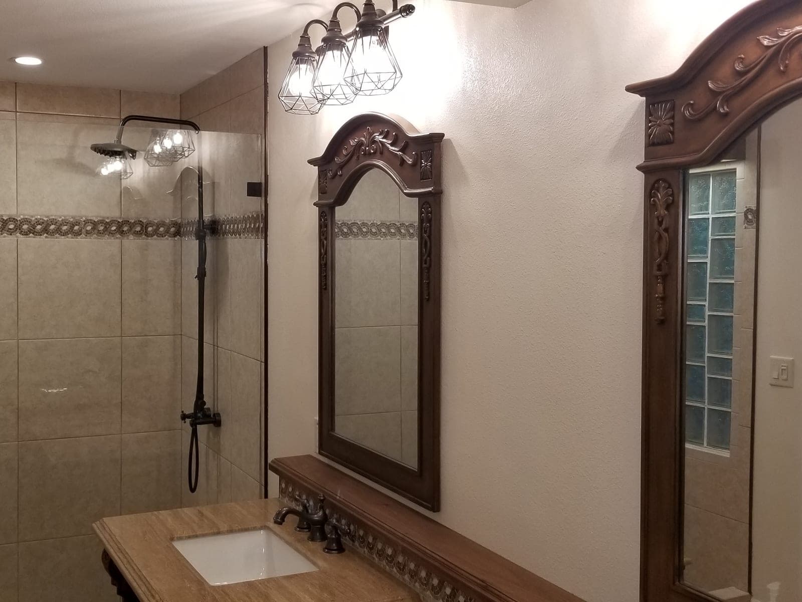Travertine walk in shower with decorative border tile and glass panel