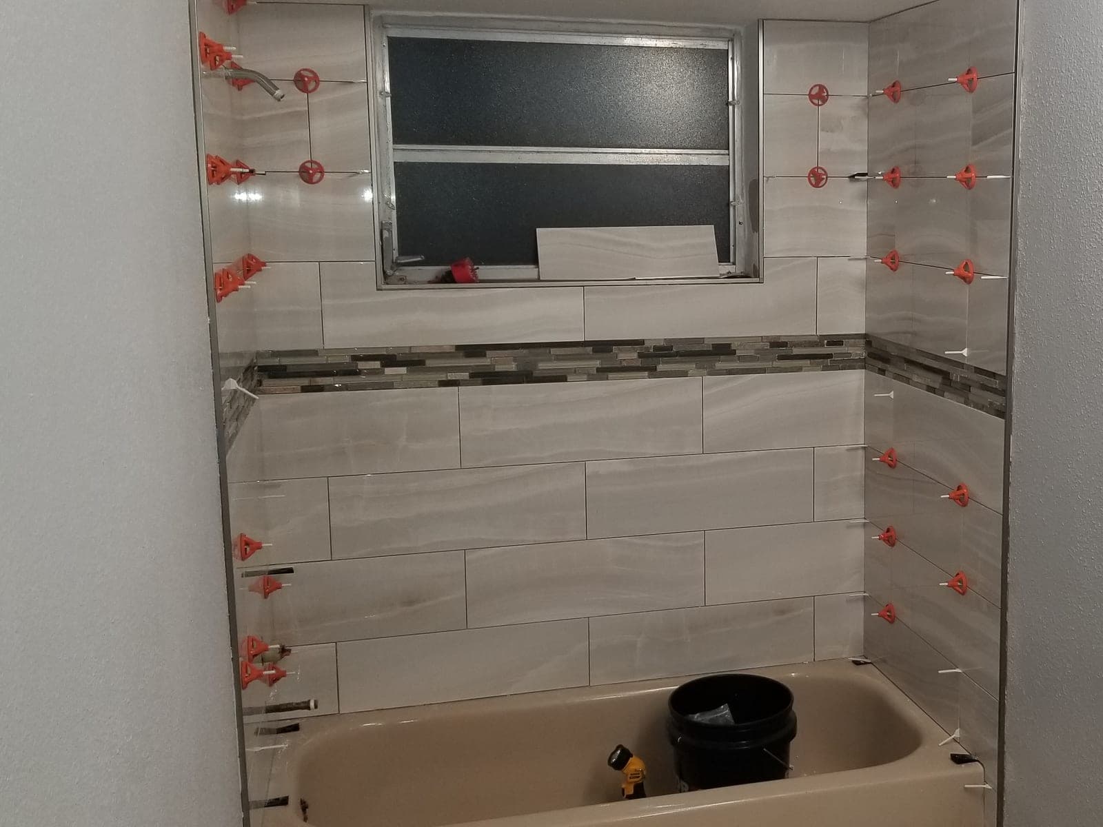 Bathroom tub surround during tile installation with leveling clips still in place