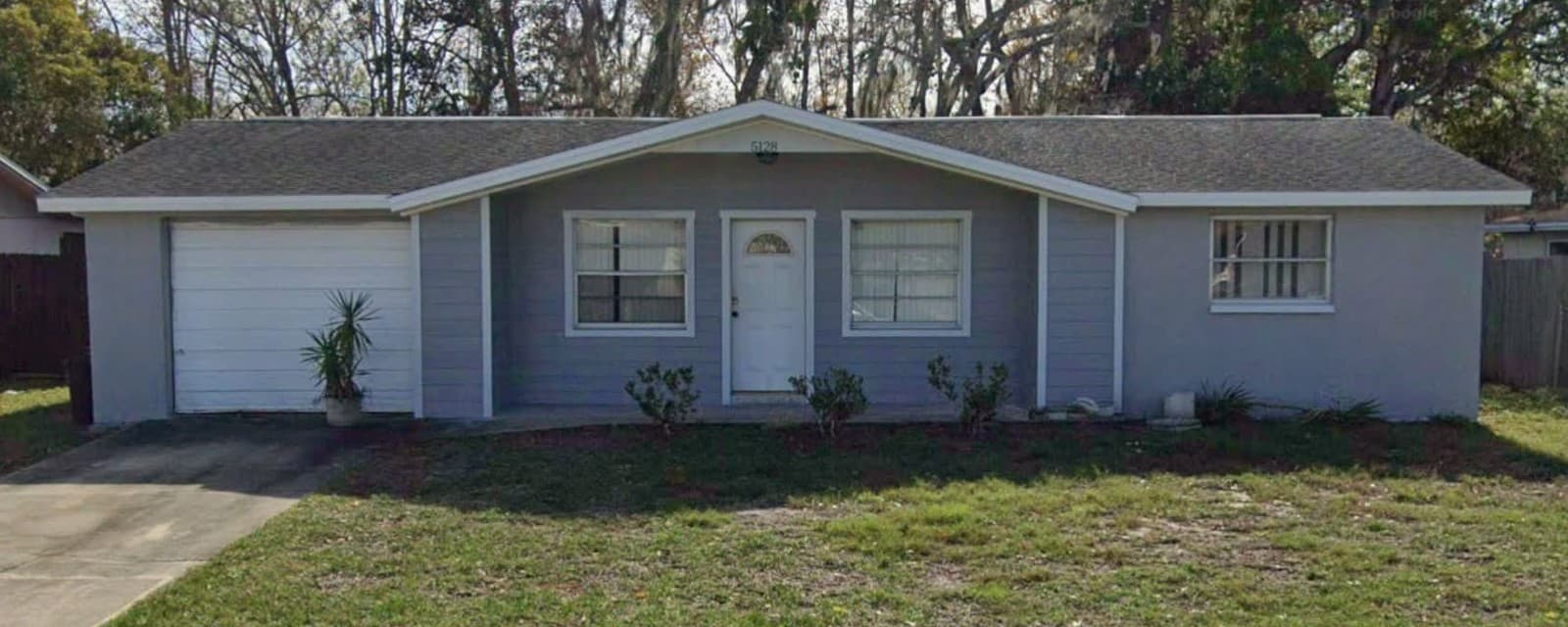 Same home after exterior work, painted gray with white trim, lap siding at the entry, and an open front porch