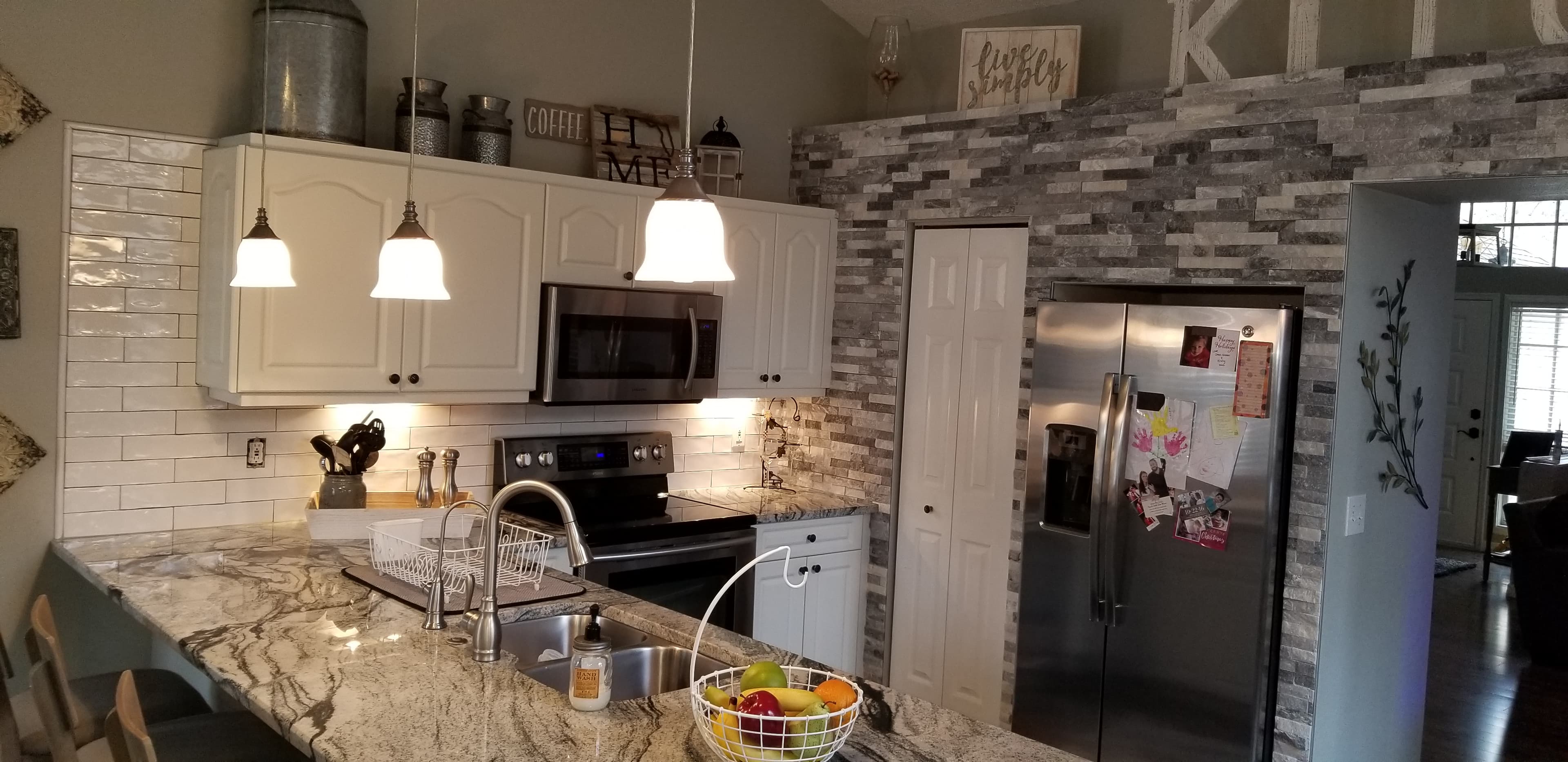Finished kitchen renovation with granite counters, pendant lighting, and white cabinets