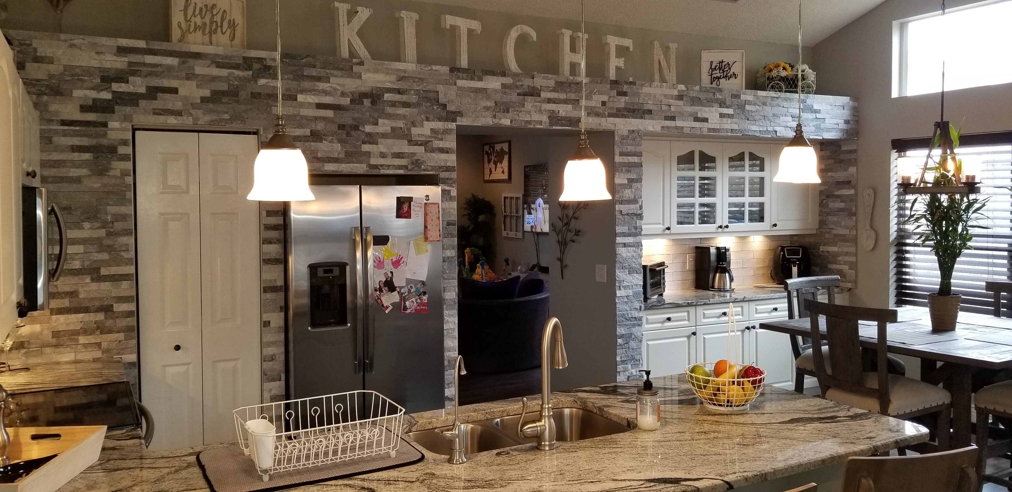 Renovated farmhouse kitchen with stacked stone accent wall by Jason Sutliff Renovations