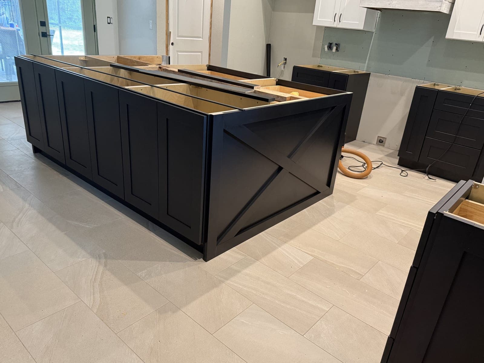 Black kitchen island with X detail end panel during cabinet installation