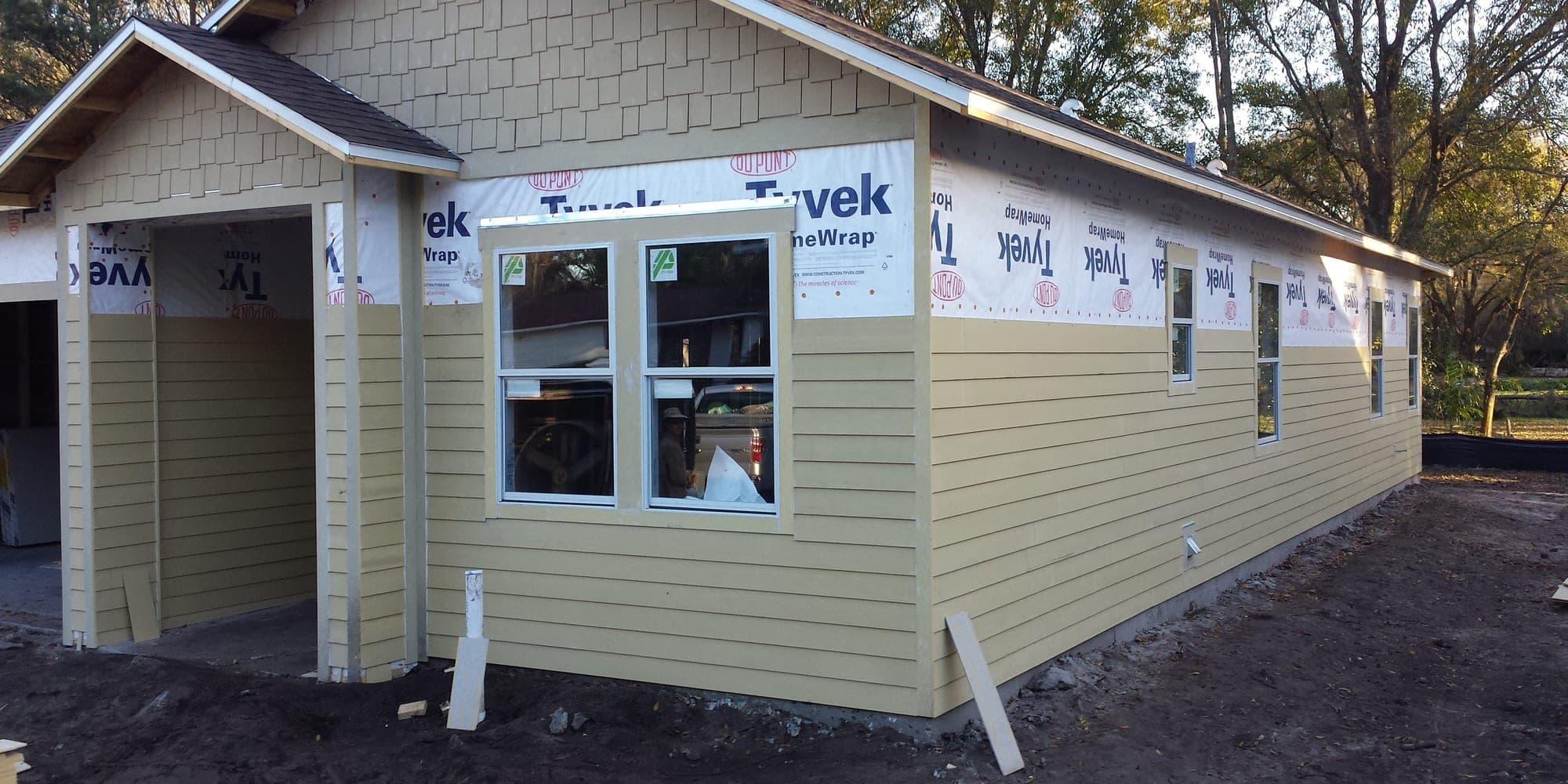 New construction home exterior during siding installation with house wrap still visible