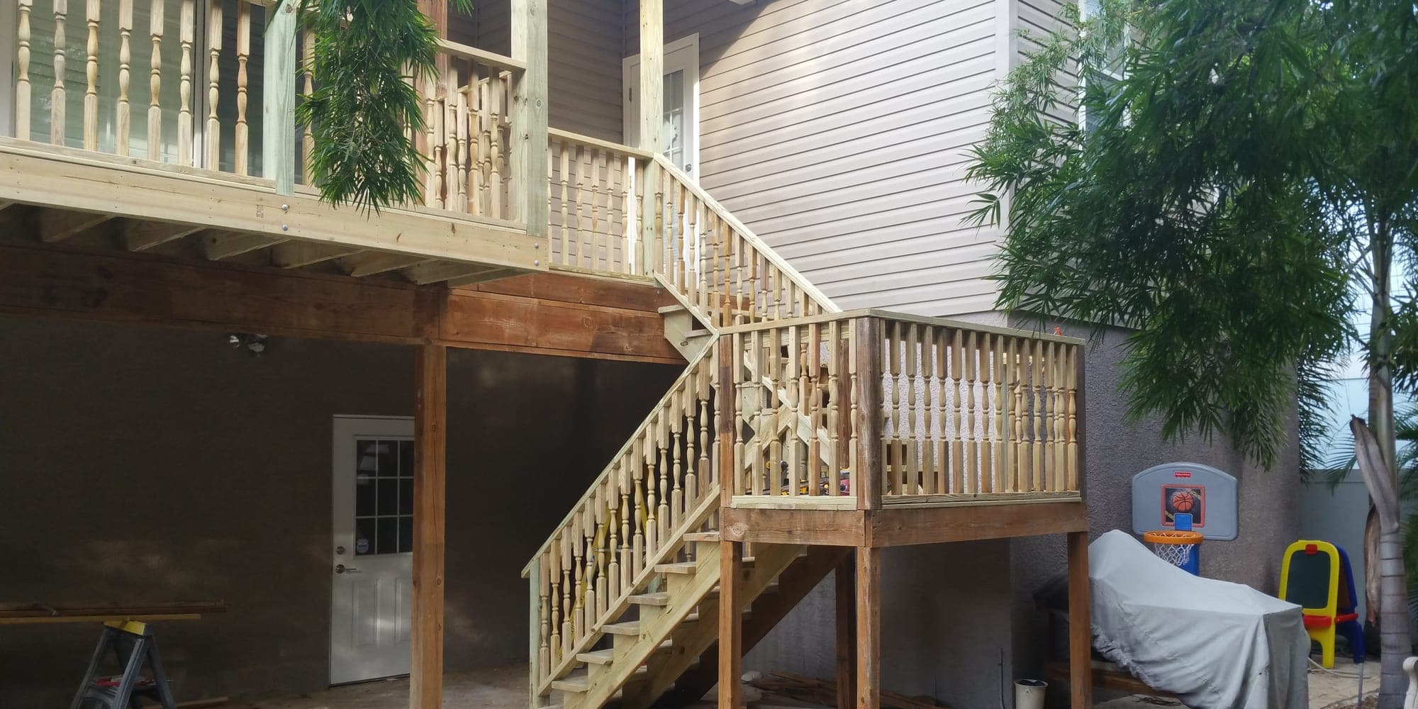 Two story porch addition during construction with framed stairs and bare deck boards