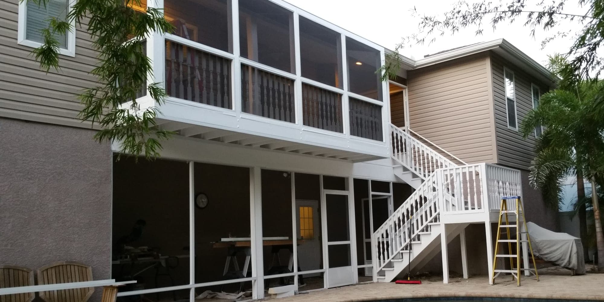 Finished two story screened porch addition with painted railings overlooking the pool