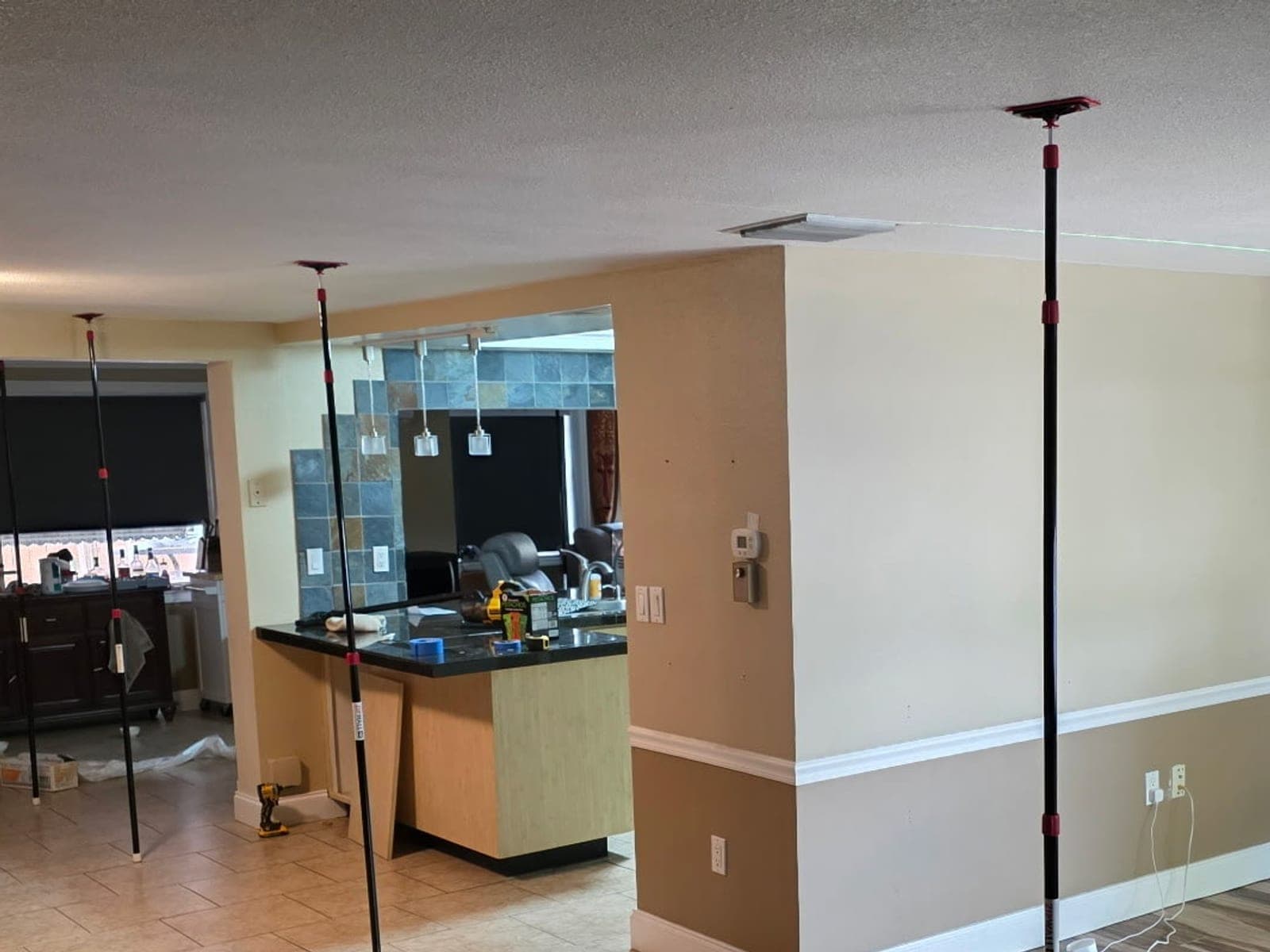 Kitchen before renovation with dark cabinets, a slate tile column, and a granite peninsula, shored during structural work
